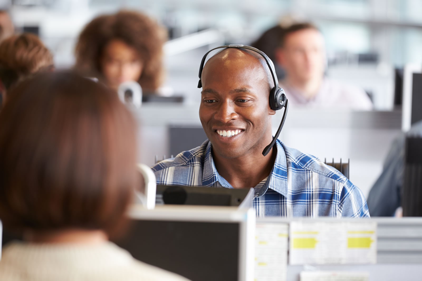 Black man working in UK call centre with headset and computer