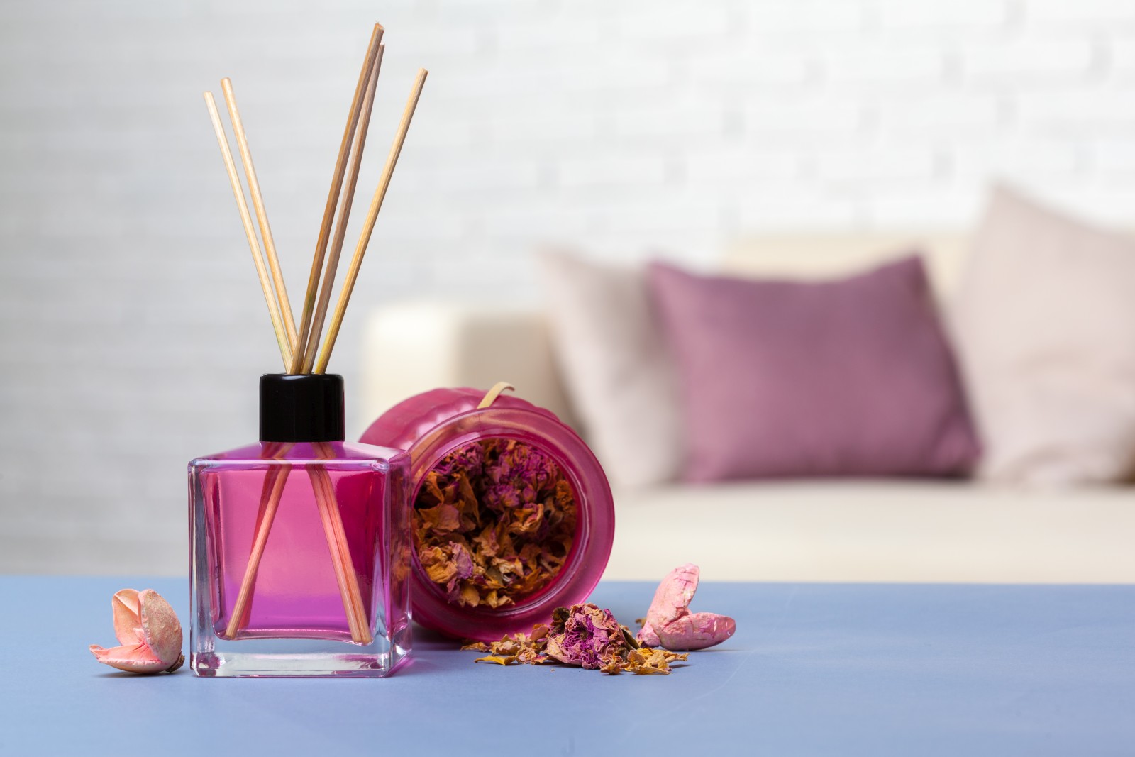 Close up of room scent sticks in a pink glass bottle in domestic setting