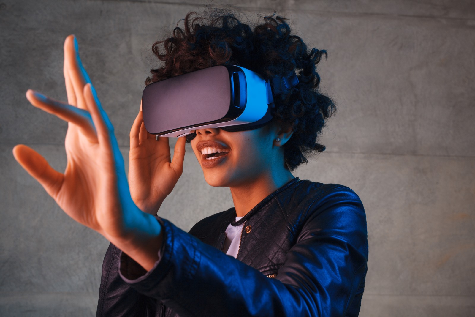 Young woman wearing virtual reality goggles and reaching out left hand in amazement
